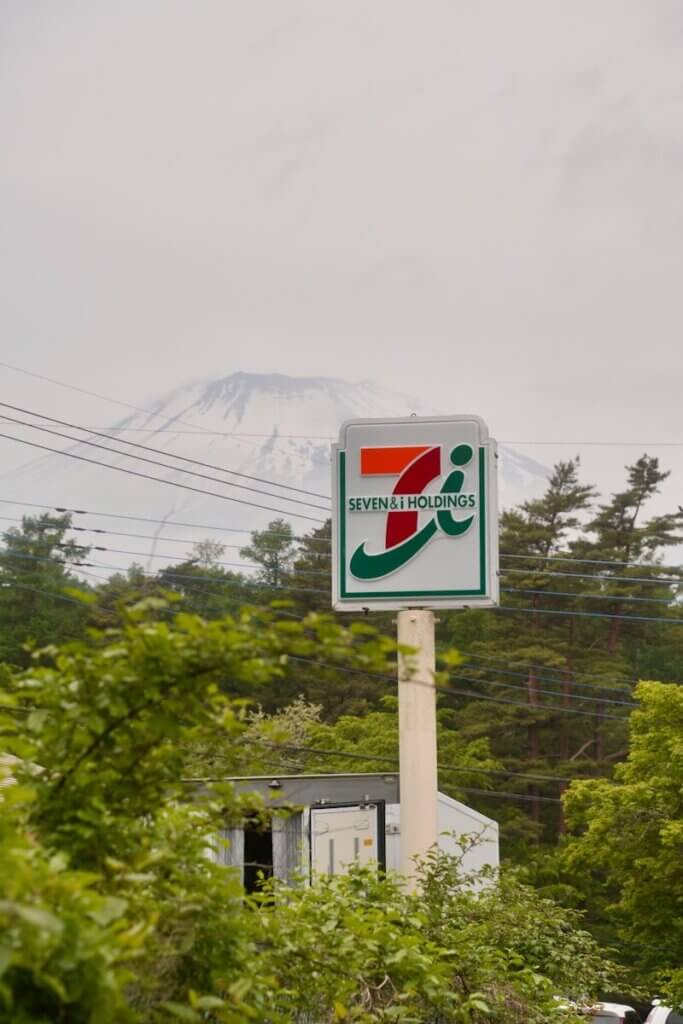 Seven-eleven sign with mount fuji in the background.